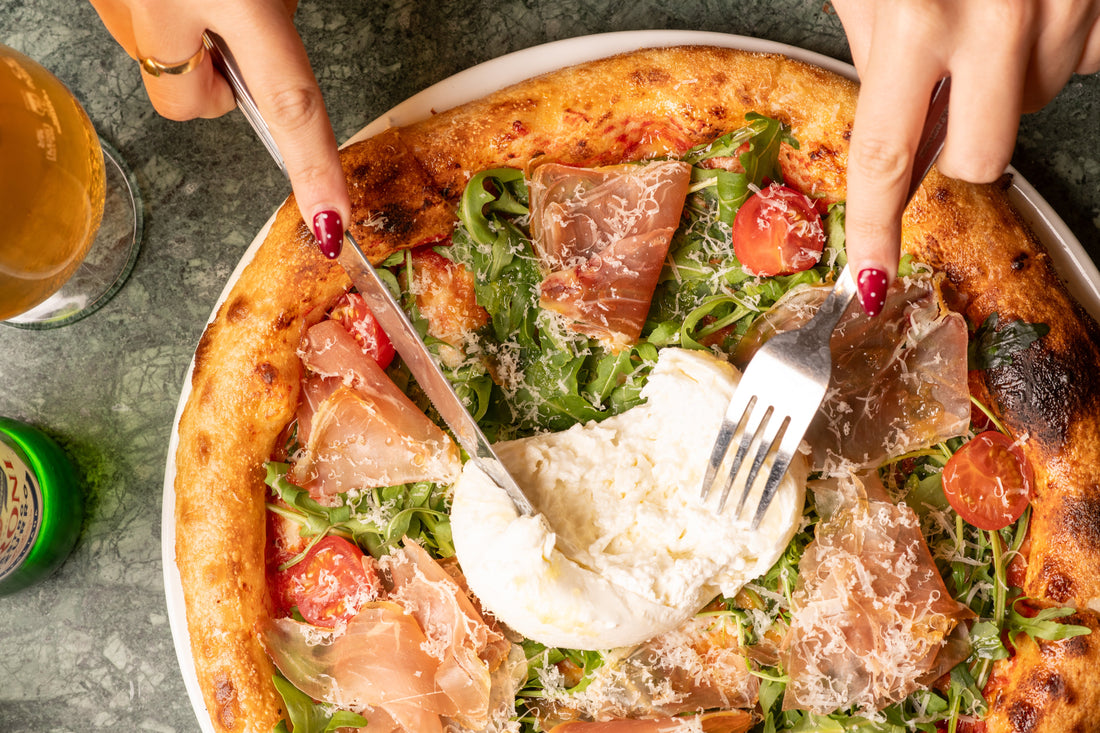 Prosciutto, rocket and burrata pizza being sliced at Fiena, King's Cross